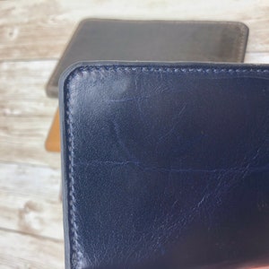 May include: A dark blue leather wallet with a stitched edge.