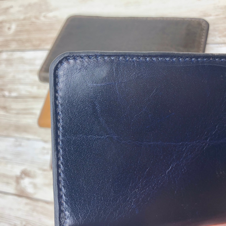 May include: A dark blue leather wallet with a stitched edge.