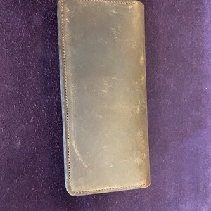 May include: A dark brown leather wallet with a stitched edge.