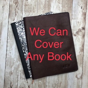 May include: A brown leather book cover with the text "We Can Cover Any Book" in red. The cover is on top of a black and white notebook.