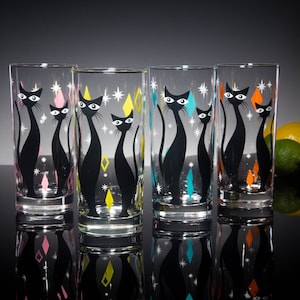 May include: Set of four clear glass highball glasses with black cat silhouettes and colorful geometric designs. The glasses have a retro mid-century modern aesthetic.