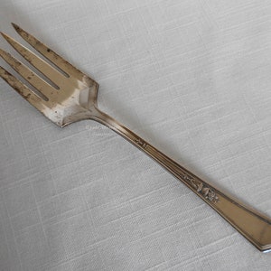 May include: A silver fork with a decorative pattern on the handle. The fork has four tines and a pointed end.