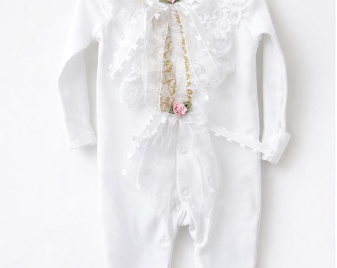 White lace romper with gold detail and pink satin flowers