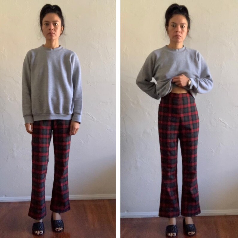 May include: A person wearing a gray sweatshirt and red and black plaid pants. The pants are a wide-leg style.