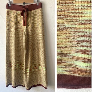 May include: Wide-leg knit pants in a brown, yellow, and green striped pattern. The pants have a drawstring waist and a brown knit waistband.
