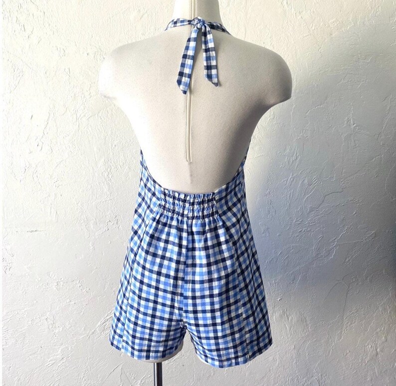 Puede incluir: Un vestido halter de vichy azul y blanco con un lazo en la parte posterior del cuello.