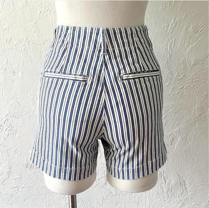 May include: White and blue striped shorts with a high waist and pockets. The shorts have a relaxed fit and are made of a lightweight fabric.