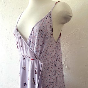 May include: A lavender maxi dress with a V-neckline and a floral print. The dress has a wrap style and a tie at the waist.