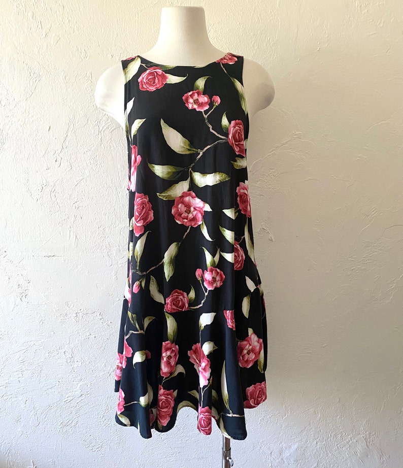 May include: A sleeveless black dress with a floral print of pink roses and green leaves.