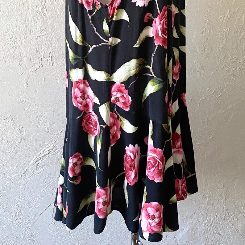 May include: A black sleeveless dress with a floral print featuring pink and white flowers. The dress has a fitted bodice and a flowing skirt.
