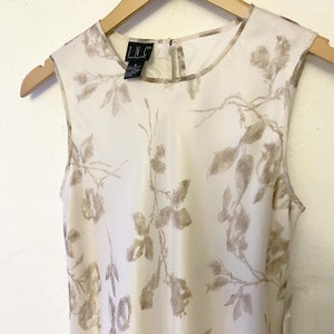 May include: A sleeveless white dress with a floral pattern in a light brown color. The dress has a round neckline and a back zipper closure. The brand label reads "I.N.C. International Concepts."