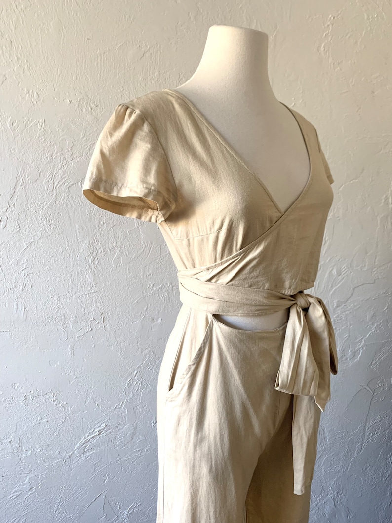 May include: A beige linen wrap top and wide-leg pants set with a tie at the waist.