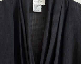 May include: Black sleeveless blouse with a deep V-neck and a textured fabric. The blouse has a label that reads "Carry Back" and "100% Polyester".