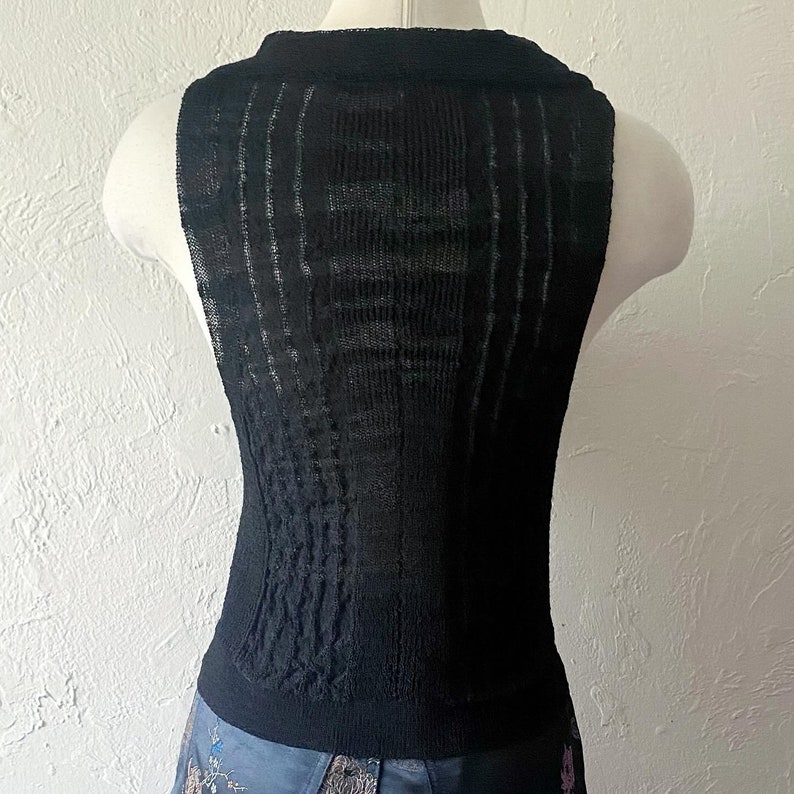 K&ouml;nnte beinhalten: Schwarzes &auml;rmelloses Strickoberteil mit einem strukturierten Muster. Das Oberteil ist aus einem leichten, atmungsaktiven Stoff.