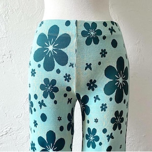 K&ouml;nnte beinhalten: Blaue Hose mit einem Blumenmuster in dunkelgr&uuml;n. Die Blumen sind ein einfaches, f&uuml;nfbl&auml;ttriges Design.