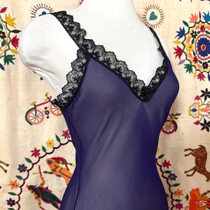 May include: A purple sheer slip with black lace trim. The slip is sleeveless and has a scoop neck.
