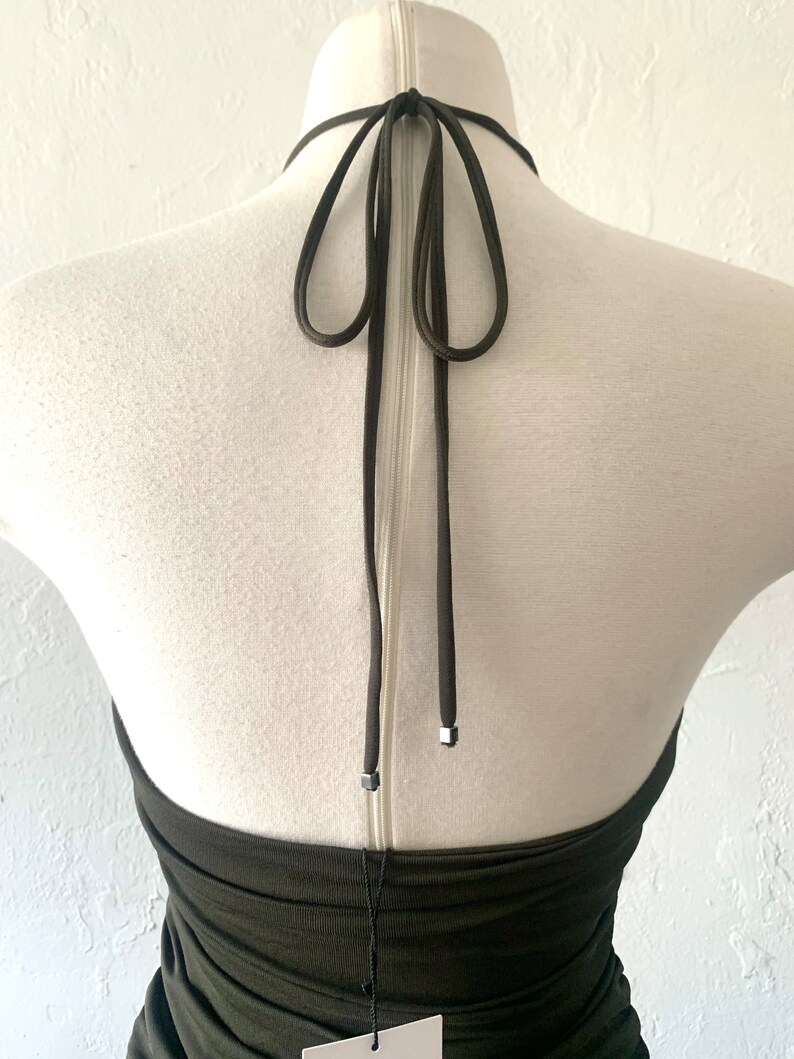 Puede incluir: Un top verde oscuro de tirantes con cierre de nudo en la espalda. El top est&aacute; hecho de una tela el&aacute;stica y tiene una silueta ajustada.