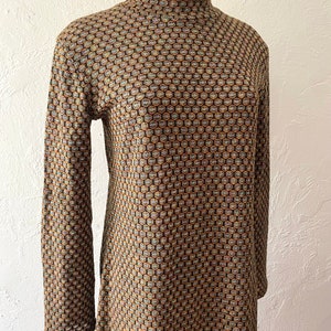 May include: A long-sleeved dress with a high mock neck and a geometric pattern in shades of brown, gold, and blue.