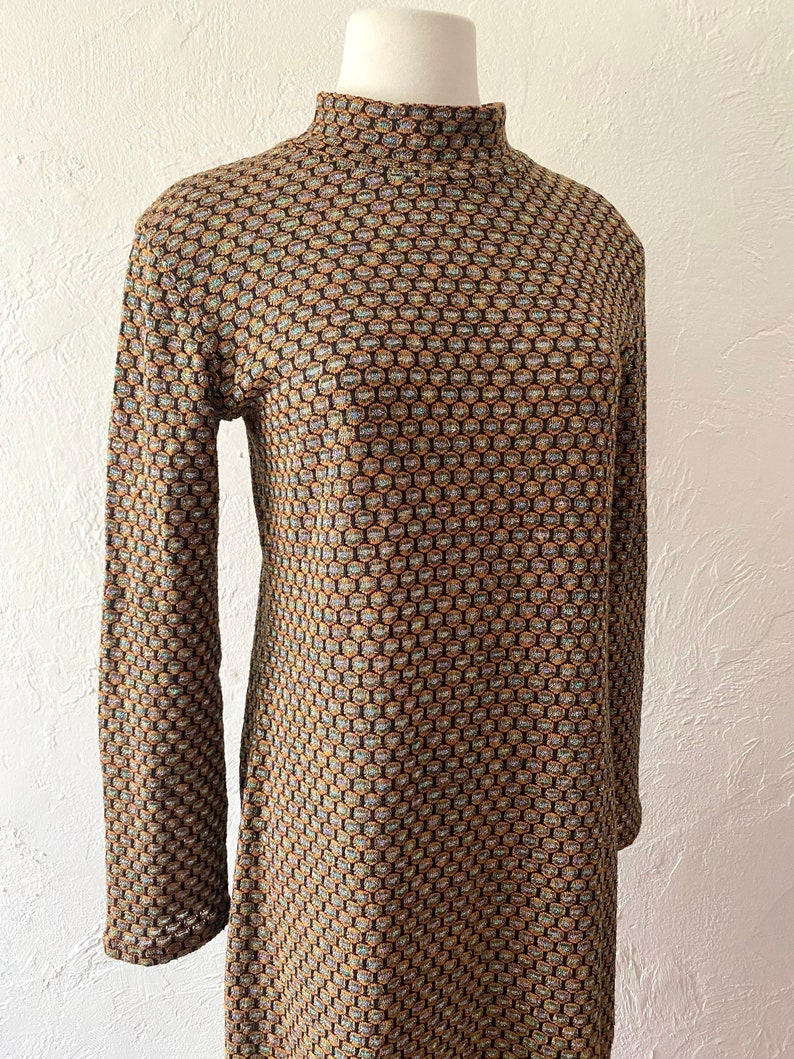 May include: A long-sleeved dress with a high mock neck and a geometric pattern in shades of brown, gold, and blue.