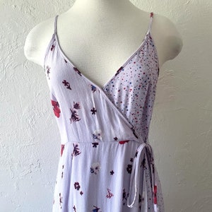 May include: A lavender wrap dress with a floral print and a tie closure. The dress has a V-neckline and a fitted bodice.