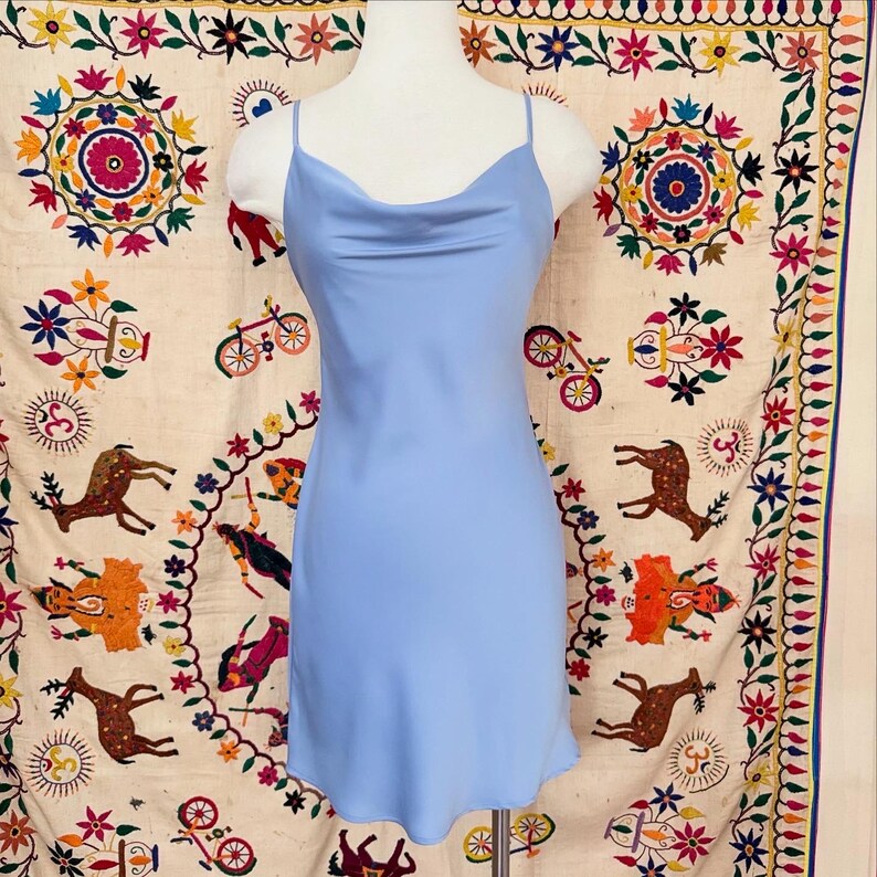 Peut inclure: Une robe de soir&eacute;e en satin bleu clair avec un col en V et des bretelles fines.