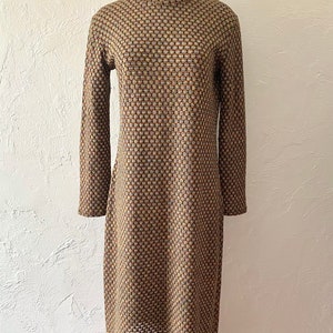 May include: A long-sleeved dress with a high mock neck. The dress is made of a brown and beige fabric with a geometric pattern.