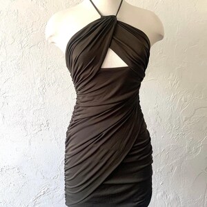 Puede incluir: Un vestido halter verde oscuro con un detalle de corte en el escote. El vestido est&aacute; hecho de una tela el&aacute;stica y arrugada.