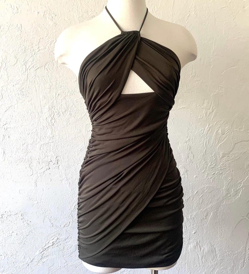 Puede incluir: Un vestido halter verde oscuro con un detalle de corte en el escote. El vestido est&aacute; hecho de una tela el&aacute;stica y arrugada.