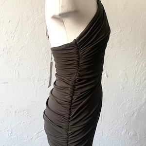 Puede incluir: Un vestido verde oscuro de un solo hombro con un corpi&ntilde;o fruncido y una silueta ajustada.