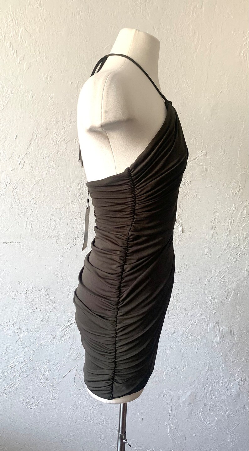 Puede incluir: Un vestido verde oscuro de un solo hombro con un corpi&ntilde;o fruncido y una silueta ajustada.