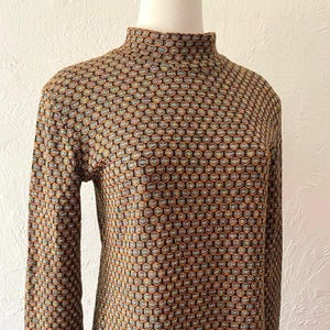 May include: A brown, black, and orange patterned turtleneck sweater with long sleeves.