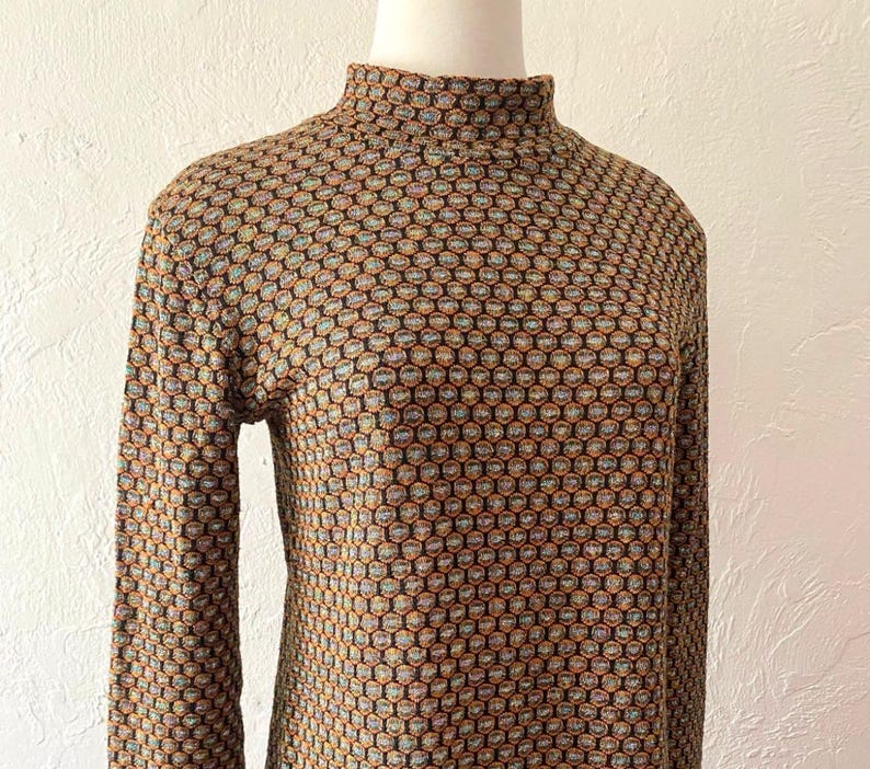 May include: A brown, black, and orange patterned turtleneck sweater with long sleeves.