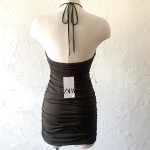 Puede incluir: Un vestido negro de tirantes con un dise&ntilde;o fruncido y una etiqueta que dice "ZARA".