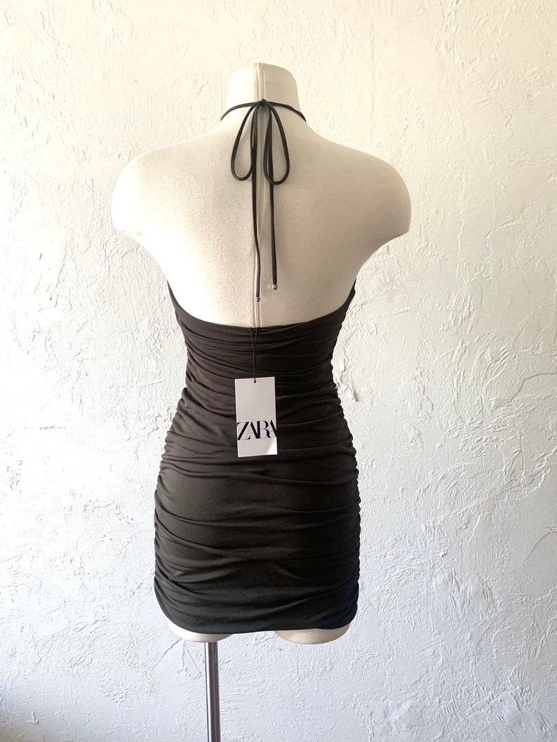 Puede incluir: Un vestido negro de tirantes con un dise&ntilde;o fruncido y una etiqueta que dice "ZARA".