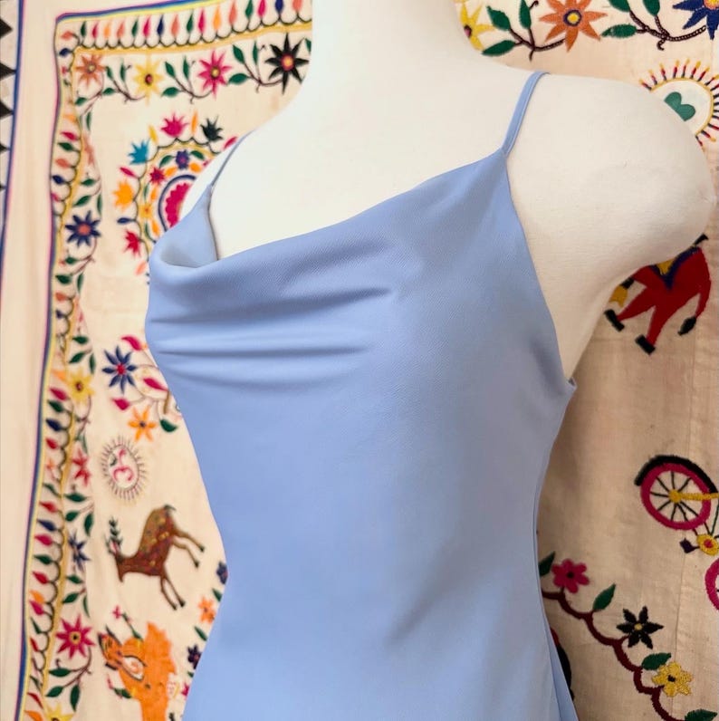 Peut inclure: Une robe sans manches bleu clair avec un col en cowl et une silhouette ajust&eacute;e.