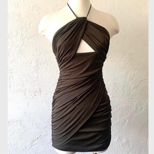 Puede incluir: Un vestido halter marr&oacute;n oscuro con un escote de ojo de cerradura. El vestido est&aacute; hecho de una tela el&aacute;stica y arrugada y tiene una silueta ajustada.