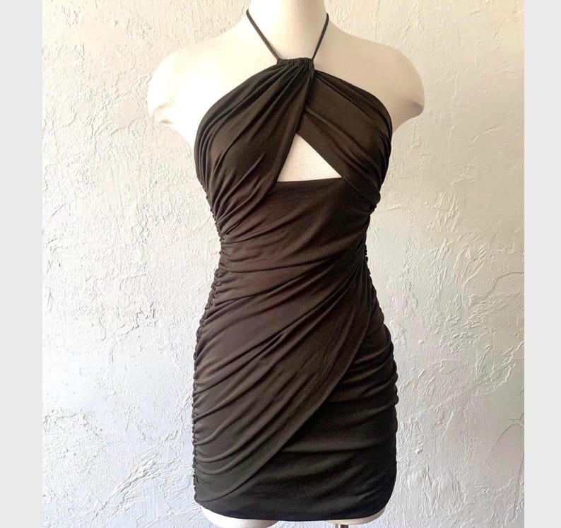 Puede incluir: Un vestido halter marr&oacute;n oscuro con un escote de ojo de cerradura. El vestido est&aacute; hecho de una tela el&aacute;stica y arrugada y tiene una silueta ajustada.