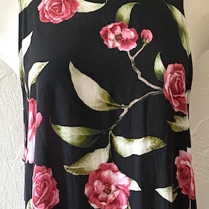 May include: A sleeveless black dress with a floral print featuring pink roses and green leaves.