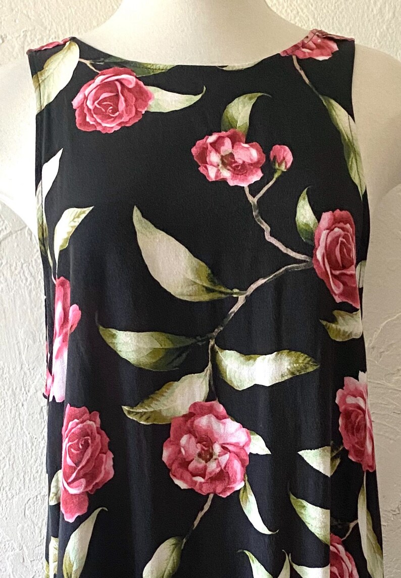 May include: A sleeveless black dress with a floral print featuring pink roses and green leaves.
