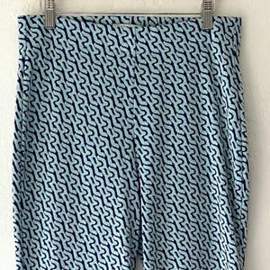 Puede incluir: Leggings estampados en azul claro y azul marino colgando de una percha met&aacute;lica. Los leggings presentan un dise&ntilde;o abstracto y repetitivo en azul marino sobre un fondo azul claro. La tela parece suave y el&aacute;stica.