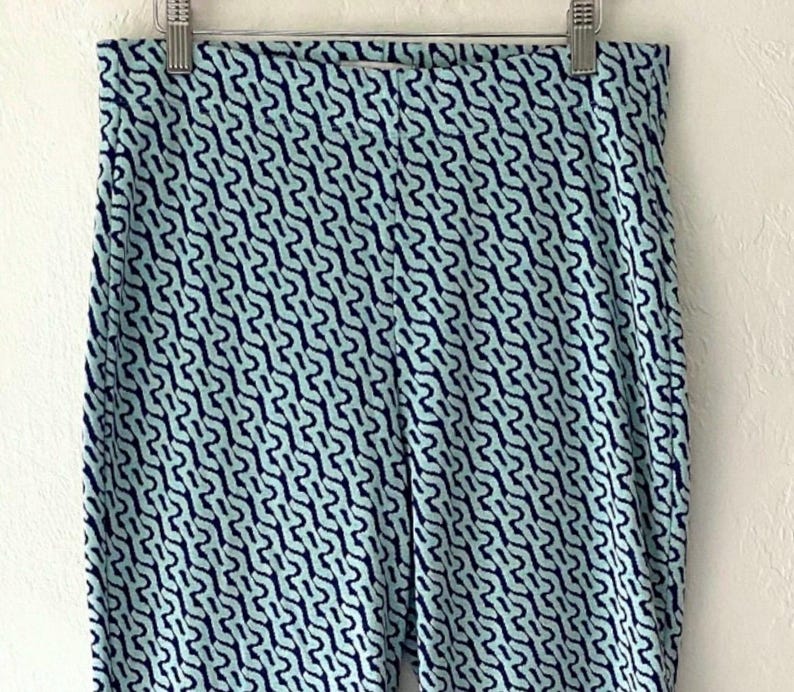 Puede incluir: Leggings estampados en azul claro y azul marino colgando de una percha met&aacute;lica. Los leggings presentan un dise&ntilde;o abstracto y repetitivo en azul marino sobre un fondo azul claro. La tela parece suave y el&aacute;stica.