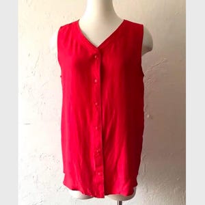 May include: A sleeveless red button-down top with a v-neck.