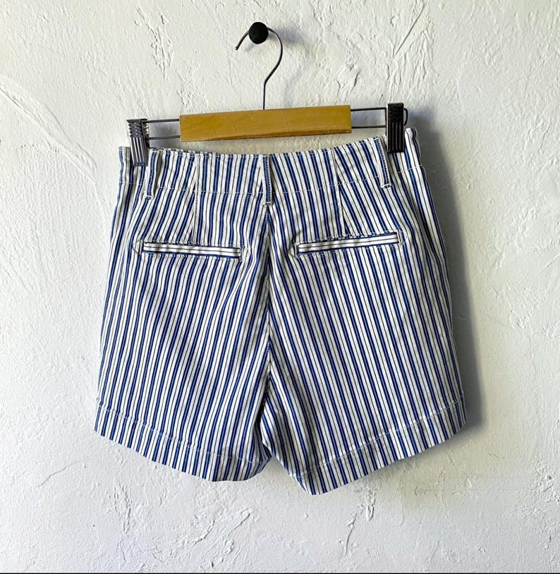 May include: Blue and white striped shorts with a high waist and pockets. The shorts are made of a lightweight fabric and have a relaxed fit.