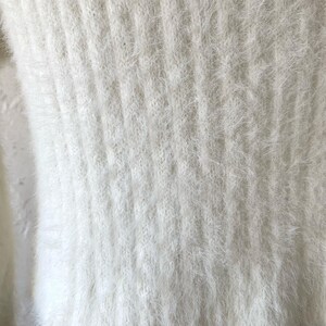 Peut inclure: Tissu en maille blanc et duveteux avec un motif textur&eacute;. Le tissu est doux et moelleux.