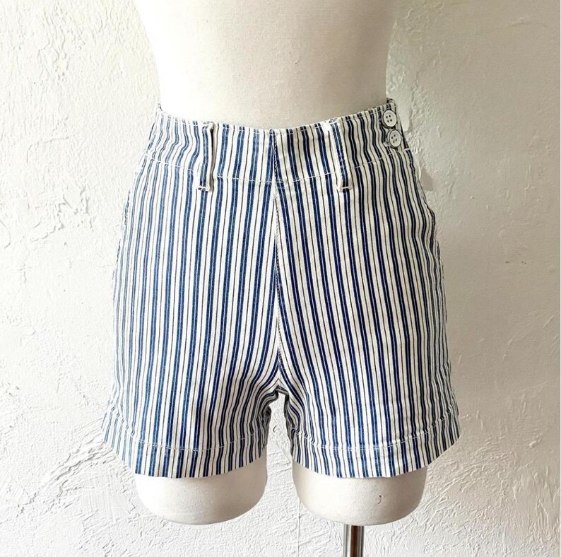 May include: White and blue striped shorts with a high waist and button closure. The shorts are made of a lightweight fabric and have a relaxed fit.