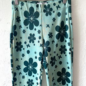 K&ouml;nnte beinhalten: Eine blaue Hose mit gr&uuml;nem Blumenmuster. Die Hose hat eine hohe Taille und ein gerades Bein.