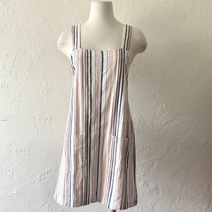 May include: A striped, sleeveless dress with a square neckline and two pockets. The dress is made of a light-weight fabric and has a relaxed fit.