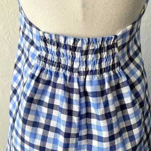 Puede incluir: Un vestido de cuadros vichy azul y blanco con una cintura el&aacute;stica fruncida.