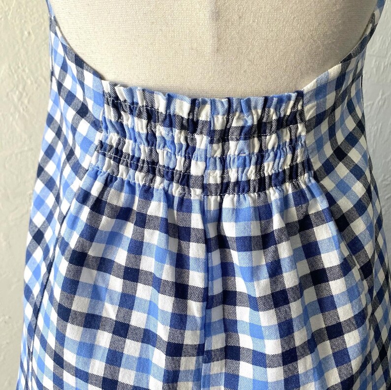 Puede incluir: Un vestido de cuadros vichy azul y blanco con una cintura el&aacute;stica fruncida.