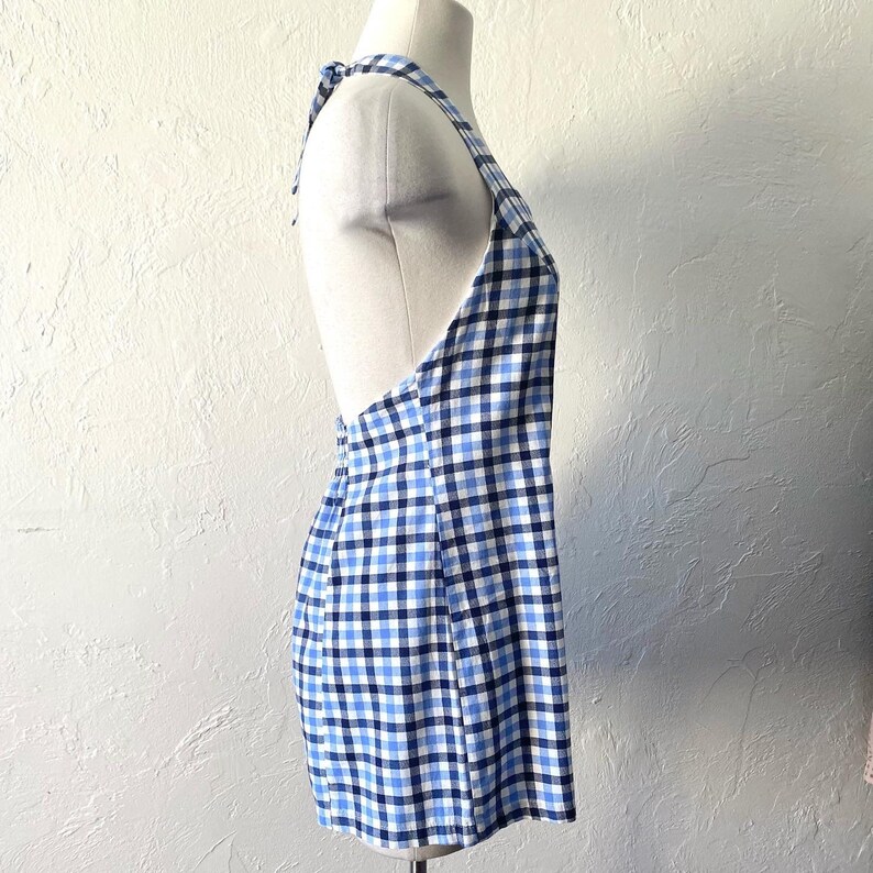 Puede incluir: Un vestido sin mangas de cuadros azules y blancos con cuello halter y lazada en la espalda.